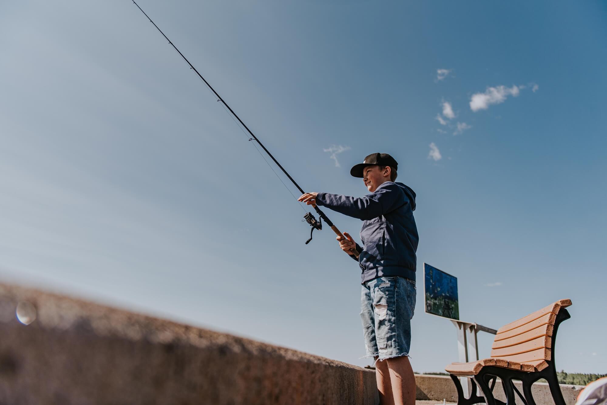 Garçon qui pêche sur le bord de l'eau